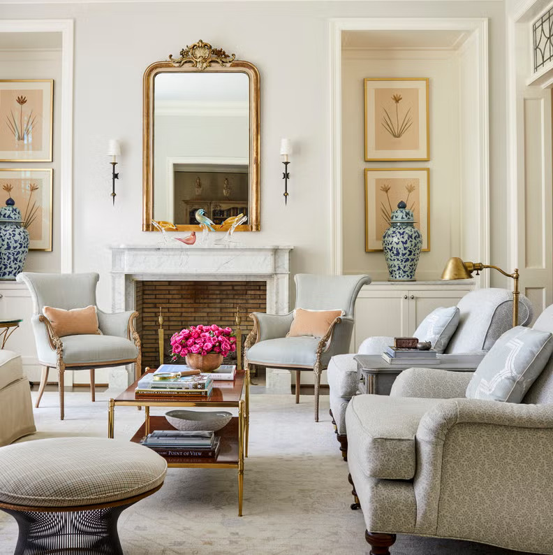 Un antiguo espejo dorado preside la repisa de la chimenea en una sala de estar formal diseñada por Joshua Pickering.