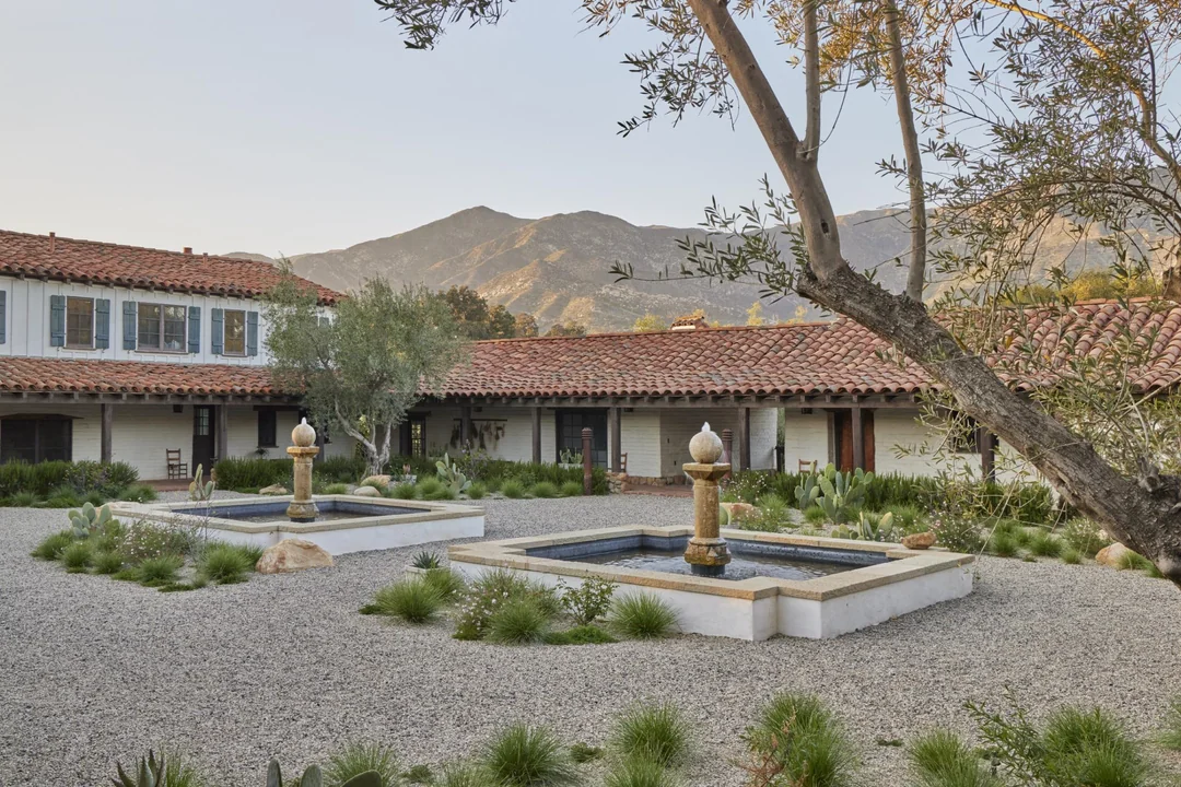 El patio central articula el conjunto: fuentes de inspiración clásica, grava y vegetación nativa en equilibrio.