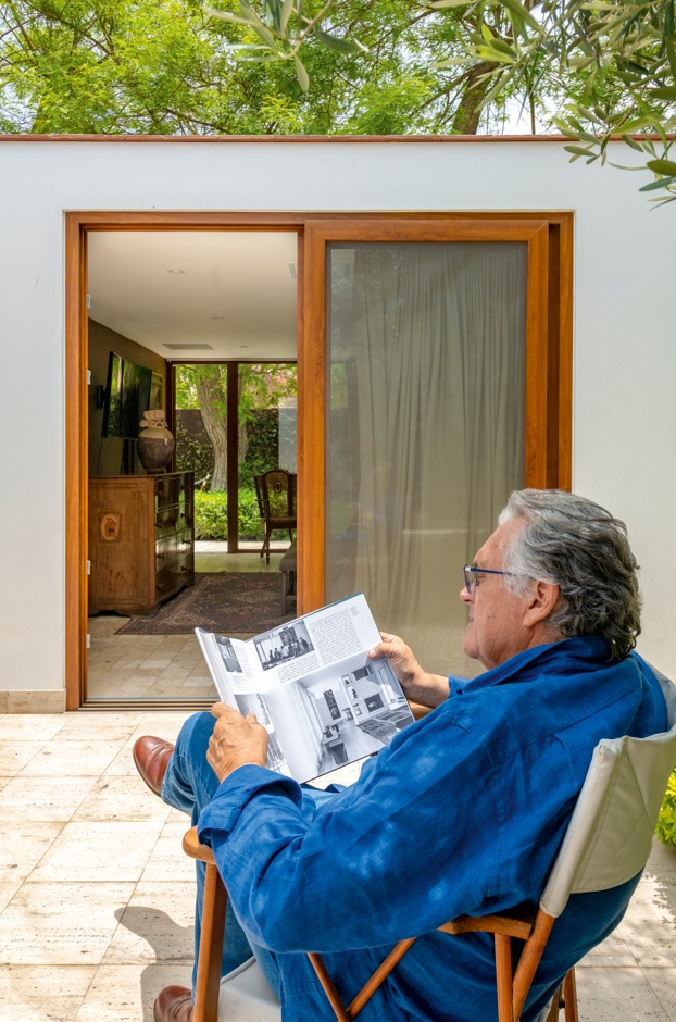 Armando Andrade revisa publicaciones sobre Sert en el umbral entre interior y jardín: una escena que resume el espíritu reflexivo y personal del proyecto.