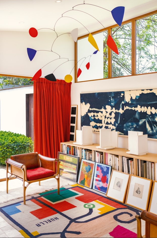 La doble altura y el ventanal corrido potencian la relación con el patio; un móvil suspendido introduce movimiento en un espacio pensado para contemplar.