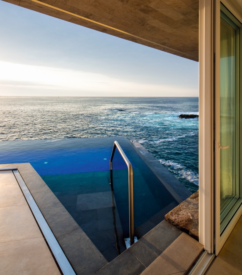 La piscina de borde infinito replica el azul profundo del mar y se convierte en el punto donde la casa parece desaparecer en el paisaje.