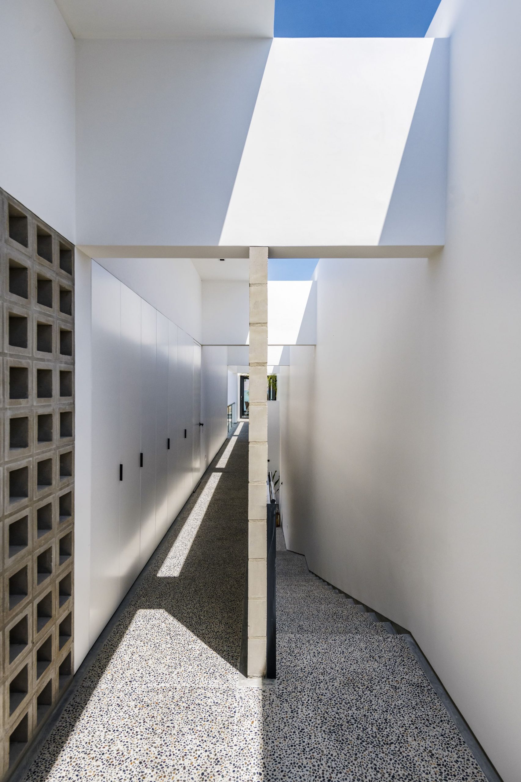 Recorridos longitudinales articulados por muros perforados que filtran luz, viento y visuales.