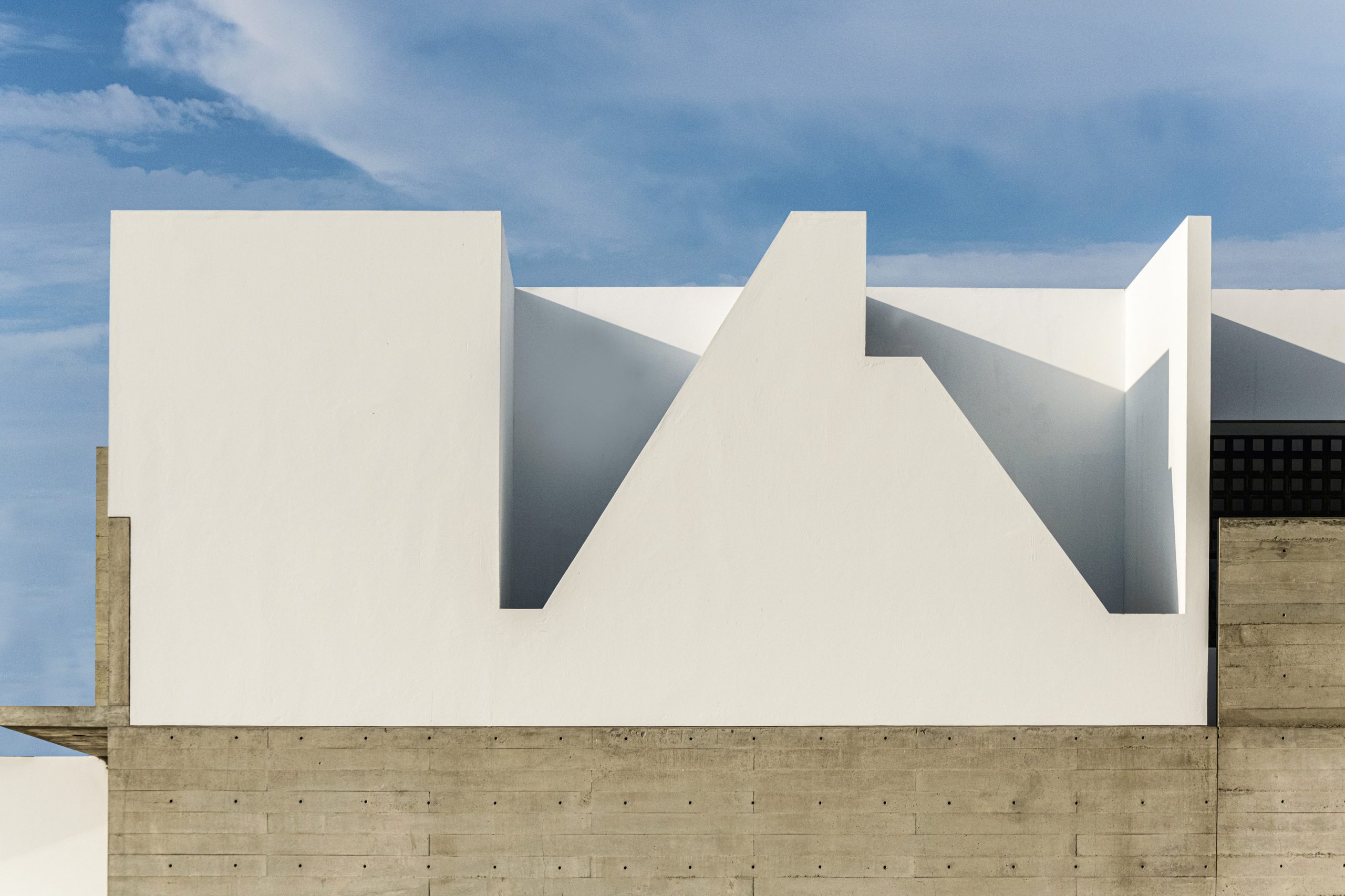 Volúmenes blancos y cortes precisos definen la fachada, una arquitectura que dialoga con el cielo y el desierto sin imponerse.