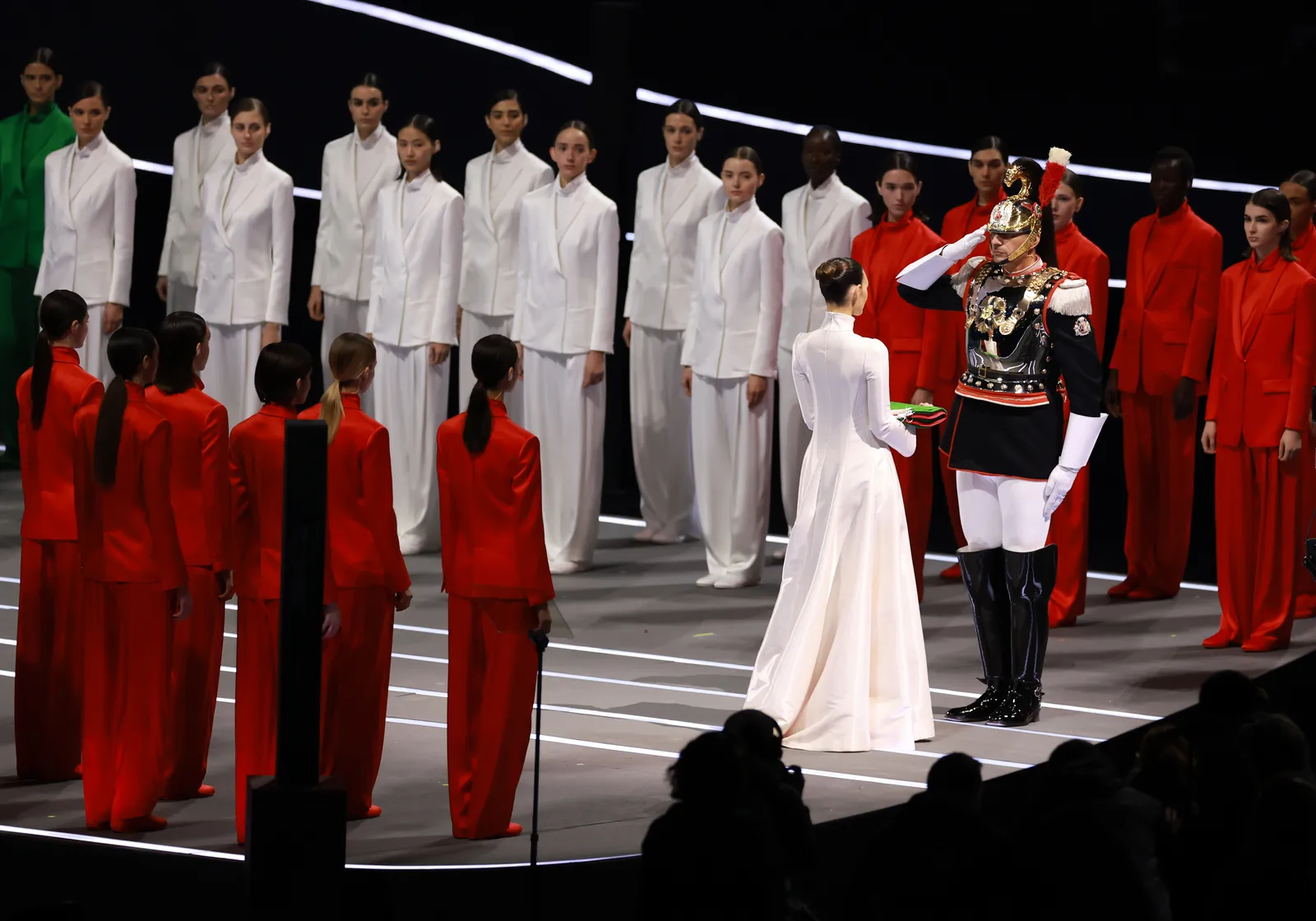Uno de los momentos más solemnes de la noche: la entrega de la bandera italiana a la guardia de honor, con Ceretti cerrando el desfile vestida de blanco.