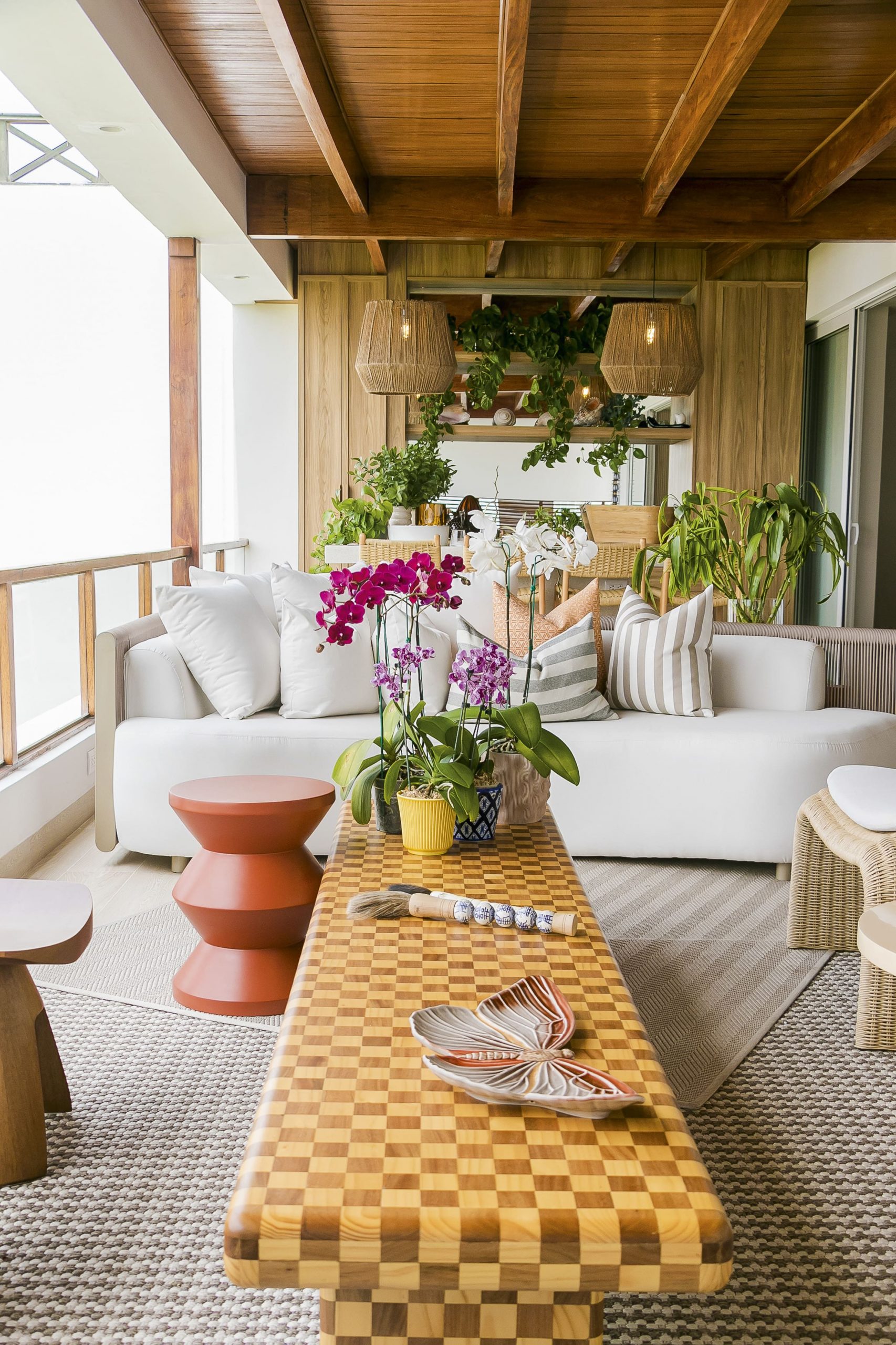 La terraza se plantea como una extensión del área social interior. La madera en pisos y vigas vistas aporta continuidad y calidez, mientras el mobiliario combina fibras naturales y acentos de color.