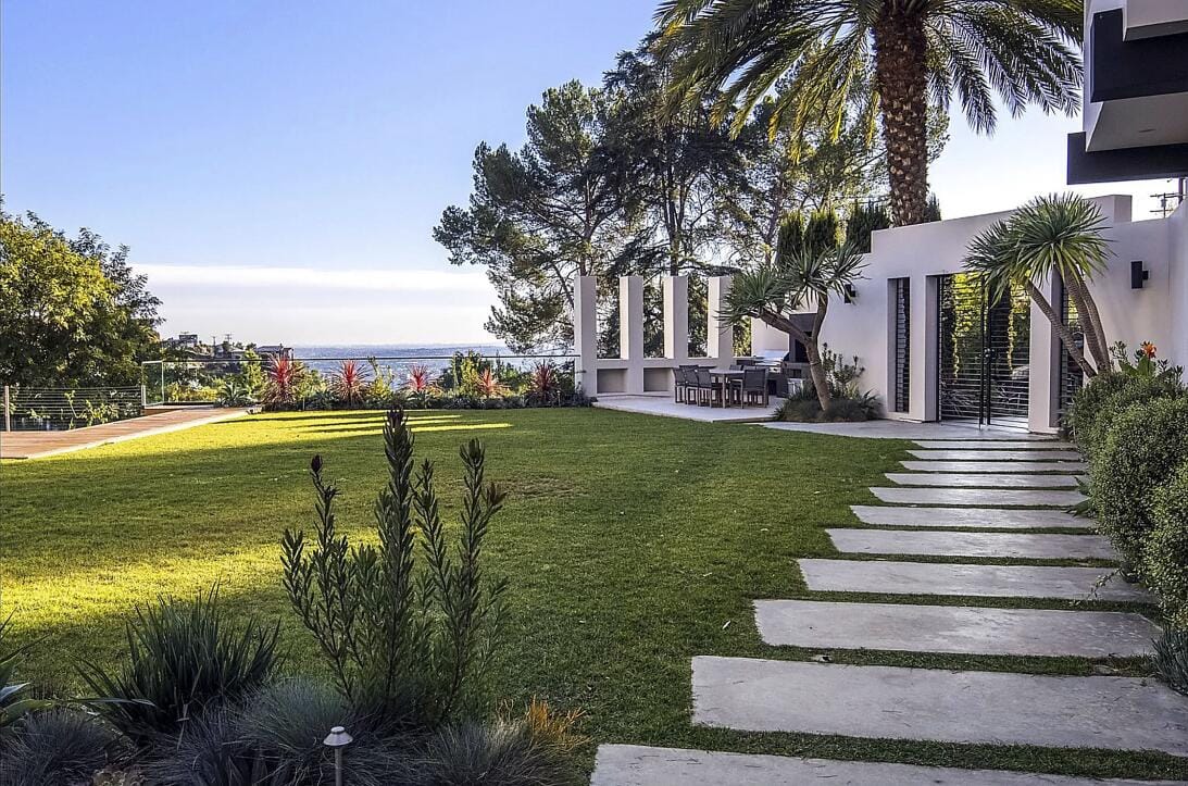 Un oasis difícil de encontrar en Los Ángeles. Jardín amplio, palmeras y áreas de descanso rodean la casa, diseñada como un santuario lejos del ruido urbano.