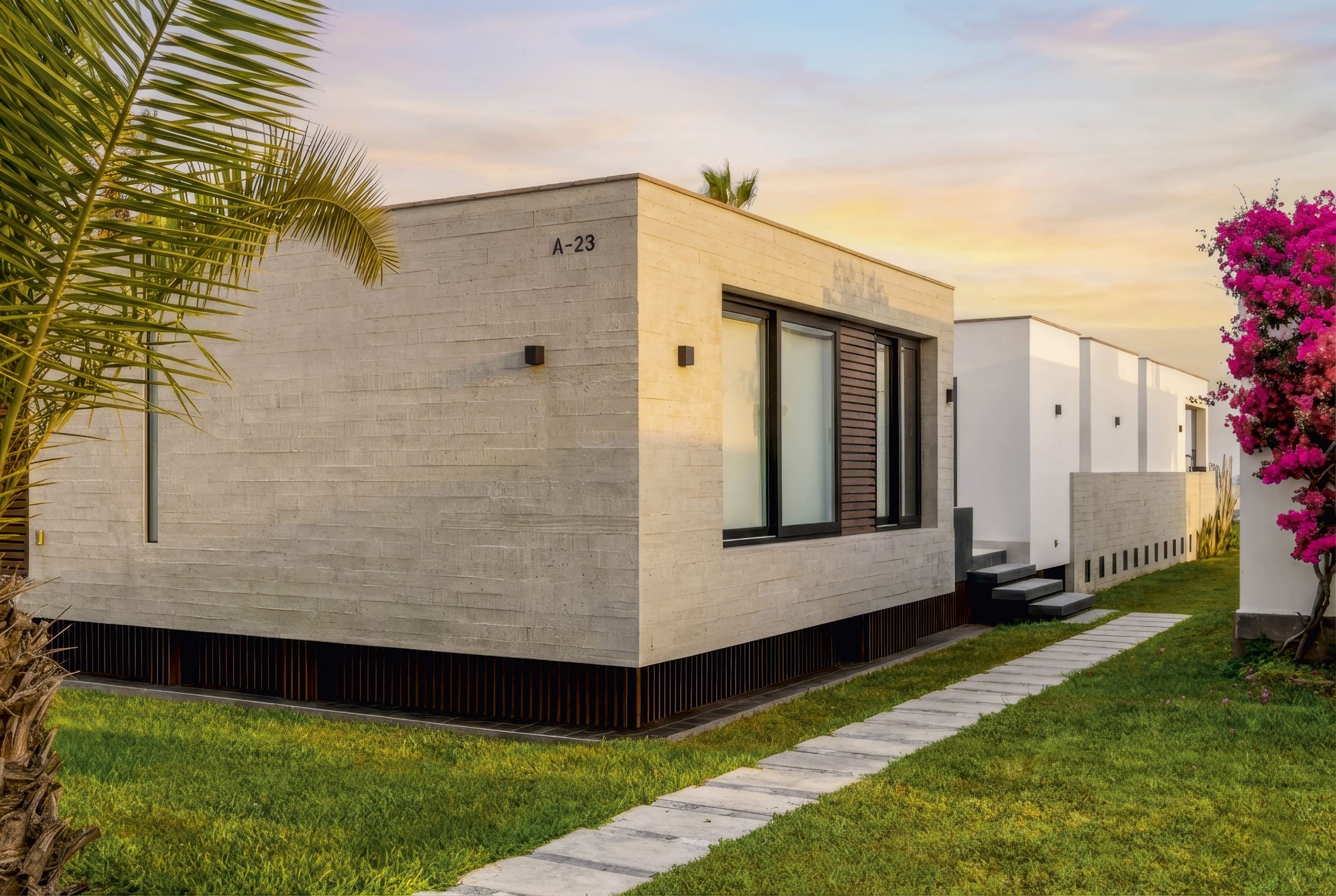 Fachada sobria y horizontal, donde el concreto y los volúmenes simples dialogan con el jardín y el clima costero.