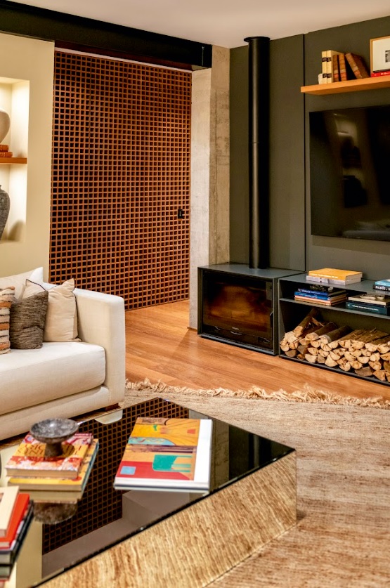 El núcleo de concreto organiza la chimenea y la televisión en un solo frente limpio, mientras la madera y la estructura metálica expuesta construyen un ambiente cálido y contemporáneo.
