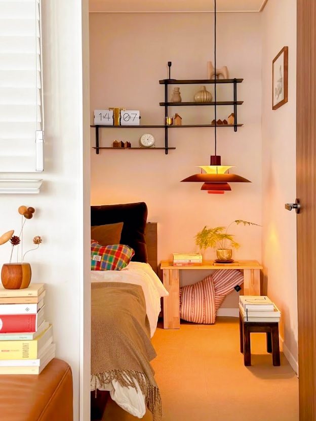 Una lámpara colgante junto a la cama aporta iluminación focal para la lectura y suma calidez al dormitorio.