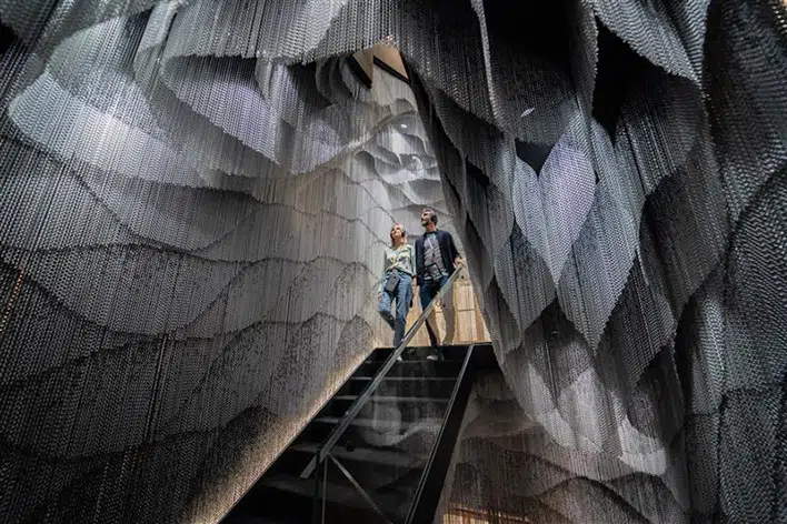 La escalinata diseñada por Kengo Kuma convierte el descenso en una experiencia sensorial envolvente, entre capas metálicas y luz filtrada.